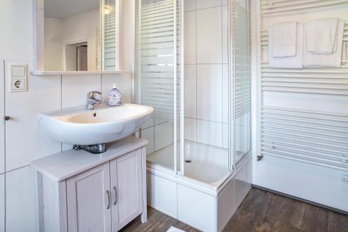a white bathroom with a sink and a shower at Gästehaus Vis à Vis in Wallhausen