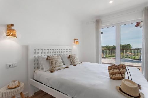 a white bedroom with a large bed and a window at Quinta dos Raposos- Nazaré Portugal in Nazaré