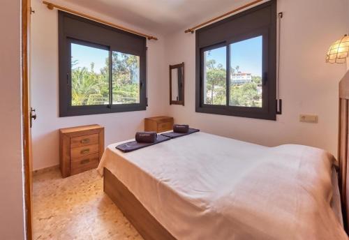 a bedroom with a large bed and two windows at Costacabana - Villa Jaruco in Lloret de Mar