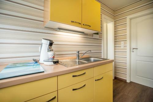 a kitchen with yellow cabinets and a sink at Kleiner Priel in Dorum