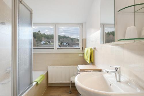 a white bathroom with a sink and two windows at Ferienwohnung Eulennestle in Lenzkirch