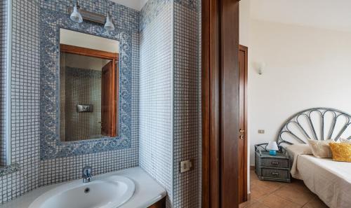 a bathroom with a sink and a mirror and a bed at Villa Mistral in Costa Rei