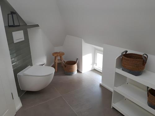 a white bathroom with a toilet and baskets at Schäferhaus in Hemme