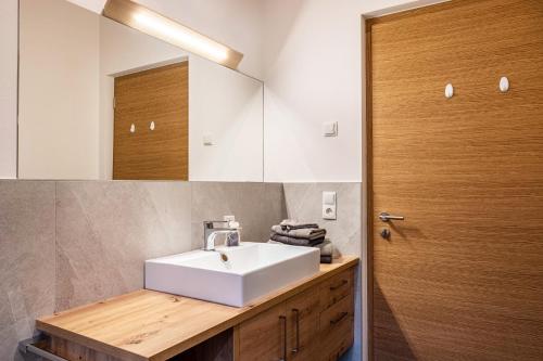 a bathroom with a white sink and a wooden door at Mittnackerhof Apartment Melisse in Sarntal