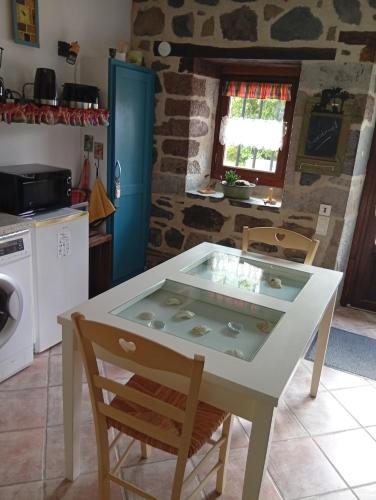 eine Küche mit einem weißen Tisch mit Stühlen und einem Herd in der Unterkunft Tiny Cantalou in Saint-Martin-sous-Vigouroux