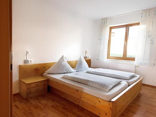 a bedroom with a large wooden bed with a window at Ferienhof Bosch in Börslingen