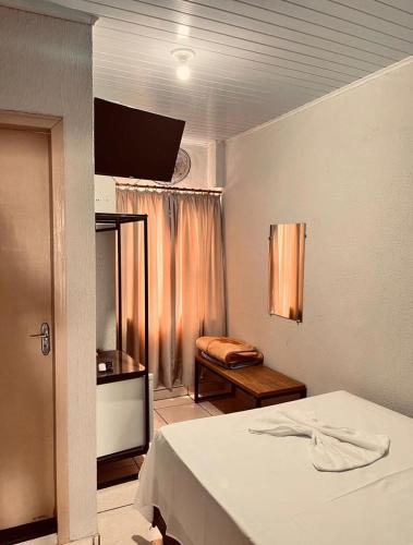 a bedroom with a bed and a table and a window at Hotel América in Ivaiporã