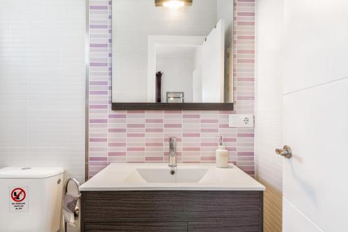 a bathroom with a sink and a mirror and a toilet at Magnolia A - Solo Familias in Conil de la Frontera