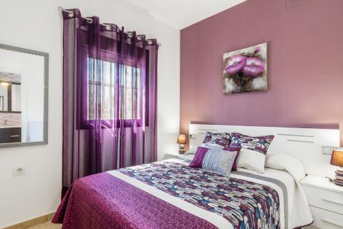 a purple bedroom with a bed and a window at Magnolia A - Solo Familias in Conil de la Frontera