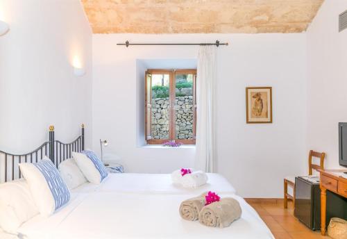 two beds in a white room with a window at Historic Finca in Mallorca Up To 8 in Andratx