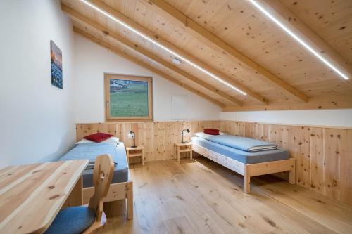 two beds in a room with wooden walls and wooden floors at Parliflhof Apt Langfenn in Meltina