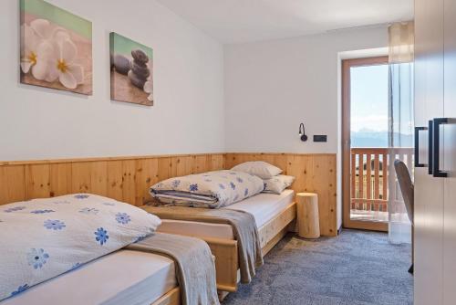 two beds in a room with a balcony at Living Lerchna -Apartment Morgentau in Maranza