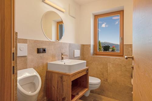 a bathroom with a sink and a toilet and a mirror at Living Lerchna -Apartment Morgentau in Maranza