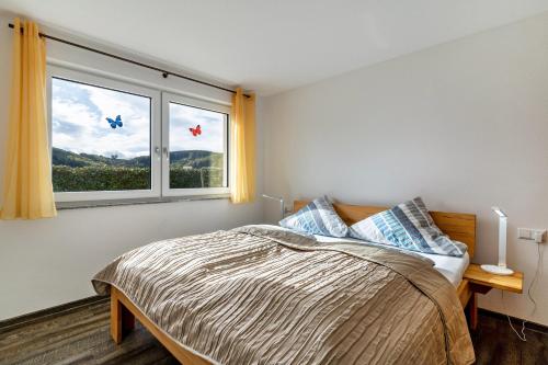 a bedroom with a bed and a large window at Ferienwohnungen Kapellenblick in Biederbach Baden-Württemberg