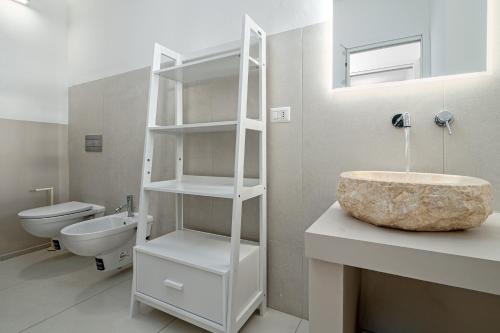 a white bathroom with a sink and a toilet at Cormorani - Appartamento 7 in Golfo Aranci