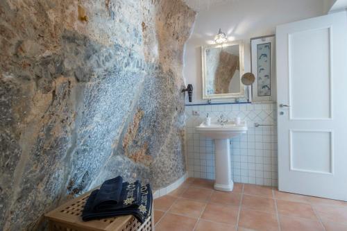 a bathroom with a white sink and a stone wall at Villa Domus Augusto in Conca dei Marini