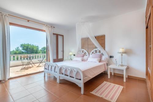 a bedroom with a canopy bed and a balcony at Can Cancus in Capdepera