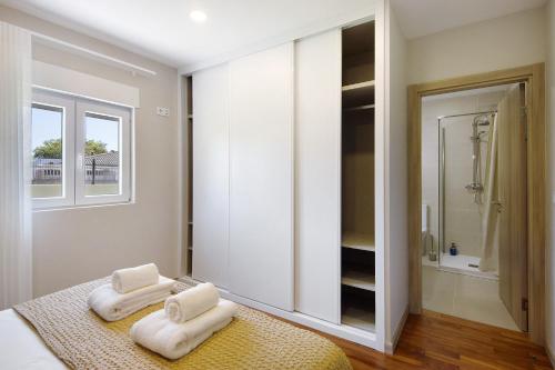 a bedroom with two white towels on a bed at Pontes Guest House in Arcozelo