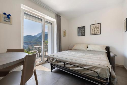 a bedroom with a bed and a table and a window at Eco del Garda Apartments in Tenno