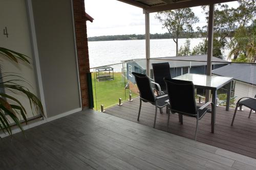 a balcony with a table and chairs and a view of the water at Dungowan Holiday Accommodation in Erowal Bay