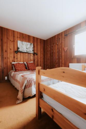 two beds in a room with wooden walls at Jean Pierre Skilodge in La Toussuire