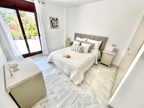 a white bedroom with a bed and a window at Villa with Private Pool in Estepona