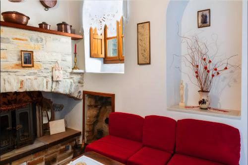 a living room with a red couch and a fireplace at Zeus House in Naxos Chora