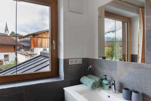 a bathroom with a sink and a mirror and a window at Ferienwohnung Haus Brugger in Uttendorf