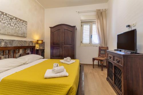 a bedroom with a bed and a television and towels at Saija Apartment con piscina in Pozzallo
