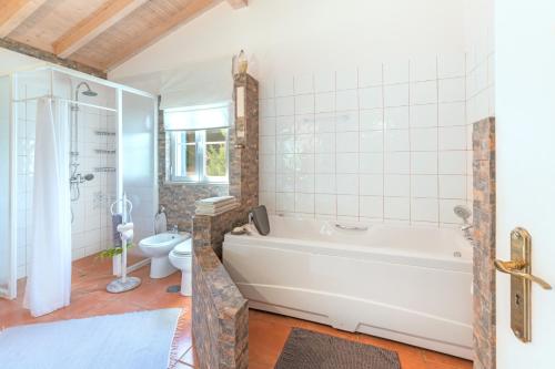 a bathroom with a white tub and a toilet at Canto do Sol - Selão da Eira in Pedreneiras