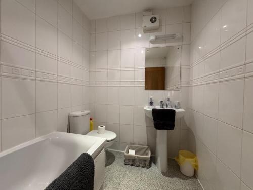 a bathroom with a tub and a toilet and a sink at Cardiff City Escapes in Cardiff