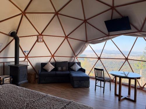 a room with a couch and a tv in a yurt at Glamping Las Nubes in Chignahuapan