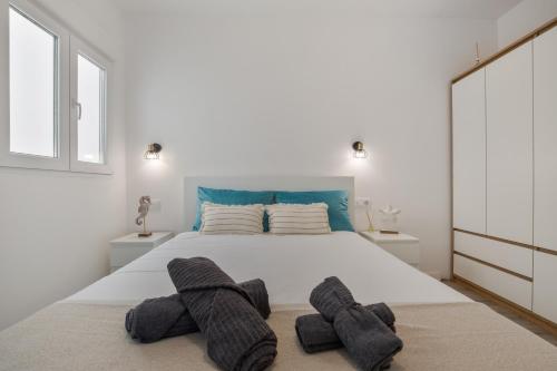a white bedroom with a large bed with two towels on it at Casa Us in Arinaga