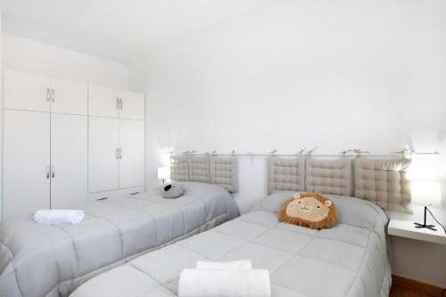 a white bedroom with two beds and a stuffed lion on the bed at Oramas Beach House – Pool & Terrace in Puertito de Güímar