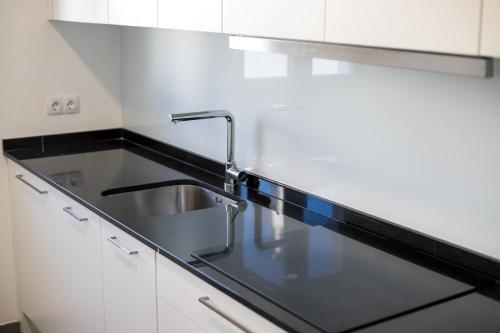 a kitchen with a sink and white cabinets at Apartamento Marei 1 in Cala Blanca