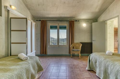 a room with two beds and a window at La Rectoría de Castellar in La Vall de Bianya