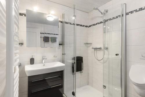 a white bathroom with a sink and a shower at Schwalbennest in Lennestadt