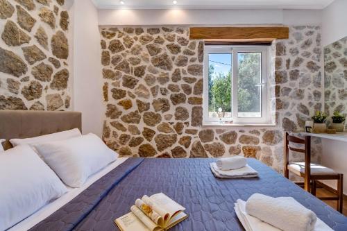 a bedroom with a stone wall with a bed and a window at Superior Apartment A in Tsoukalades