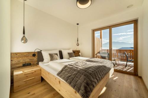 a bedroom with a large bed and a balcony at Apt Zirbe - Nockerhof in Andrian