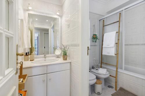 a white bathroom with a toilet and a sink at Ria's Birds in Cabanas de Tavira