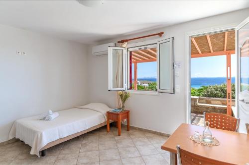 a bedroom with a bed and a table and a window at Anemologio 203 Tinos in Agios Ioannis