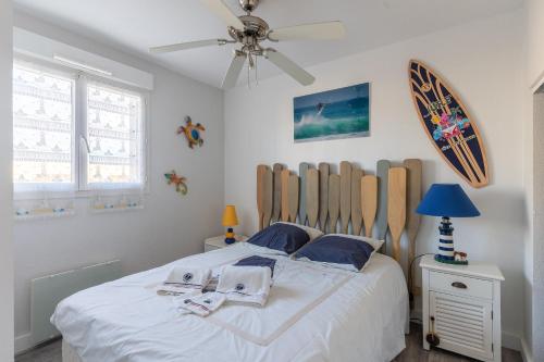 a bedroom with a white bed with a wooden headboard at Appartement Première ligne plage in Mimizan