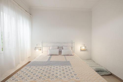 a white bedroom with a large bed with two pillows at Playa Sol Vinaròs in Vinarós