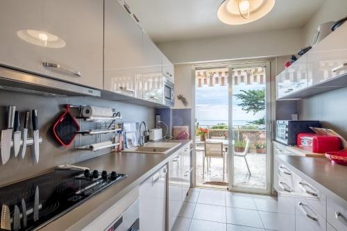 eine Küche mit weißen Schränken und einem großen Fenster in der Unterkunft Le Monfleury in Villeneuve-Loubet
