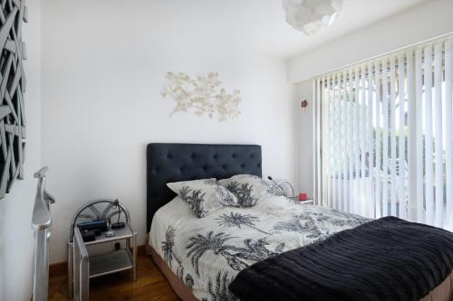 ein Schlafzimmer mit einem Bett mit schwarzem Kopfteil und einem Fenster in der Unterkunft Le Monfleury in Villeneuve-Loubet
