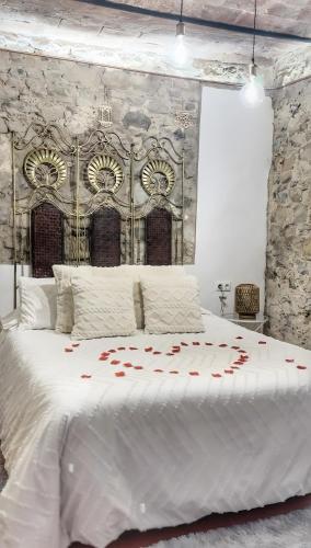 a large white bed with red rose petals on it at La Casa Arabe in Alcalá de los Gazules