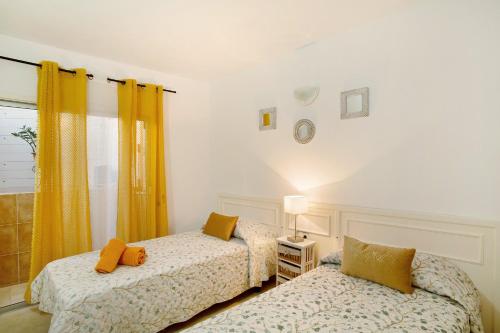 two beds in a room with yellow curtains at Apartamento Danoe 2 in Mogán