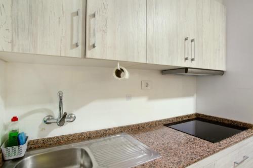 a kitchen with white cabinets and a sink at Apartamento Danoe 2 in Mogán