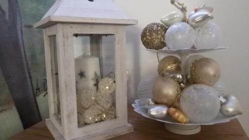 a table with a lantern and a plate of christmas ornaments at Affittacamere Rubino Guest House in Ponte nellʼAlpi