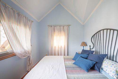 a bedroom with a bed with blue pillows and a window at Casa Nueva de Bueu in Bueu